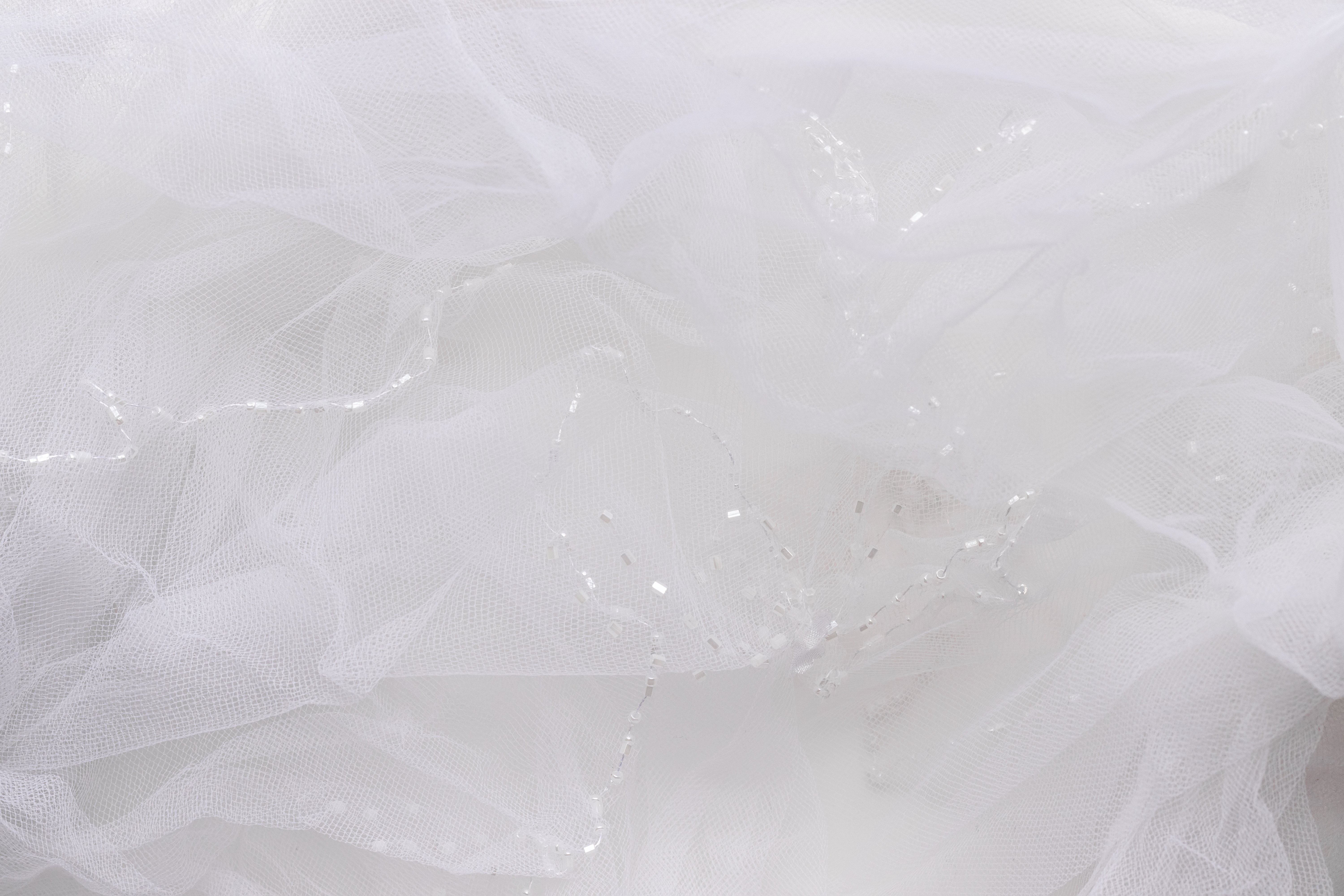 Delicate White Tulle Background. Blurred Wedding Veil with Beads Closeup